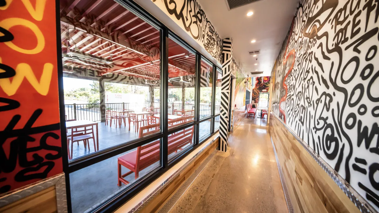 Interior view of Dave's Hot Chicken on Haynes Bridge Rd, Alpharetta, GA, featuring vibrant murals and red seating.