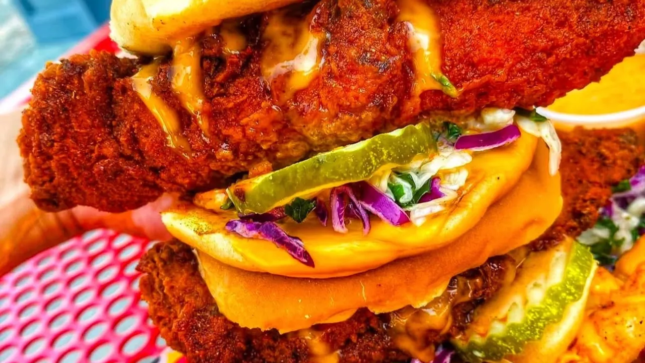 Delicious stacked chicken sandwiches with pickles and slaw from Dave's Hot Chicken in Fountain, CO, showcasing vibrant colors.