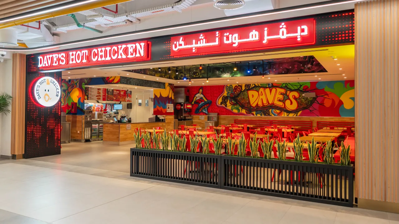Interior view of Dave's Hot Chicken at Unit #GF-AR-04, Sheikh Mohamed Bin Salem Road, Ras Al Khaimah, featuring vibrant murals and red seating.