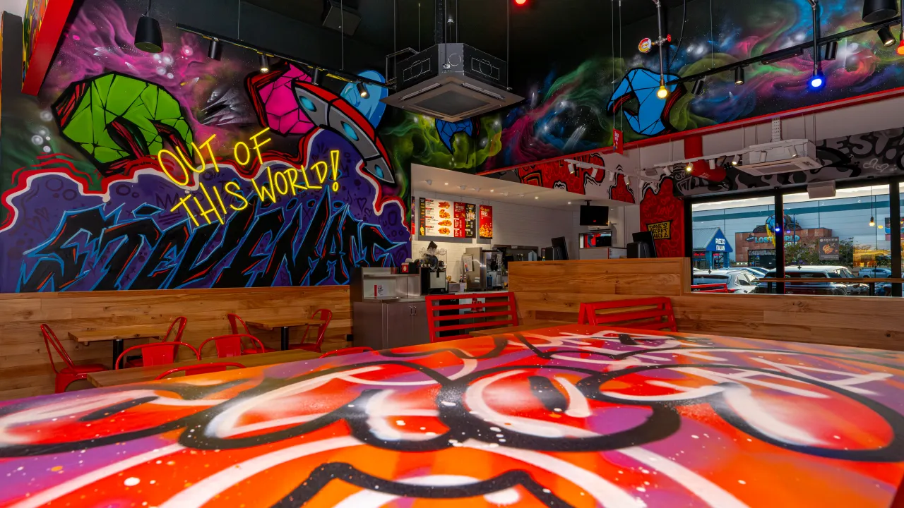 Interior view of Dave's Hot Chicken at Stevenage Leisure Park, Stevenage, UK, showcasing vibrant murals and red seating.