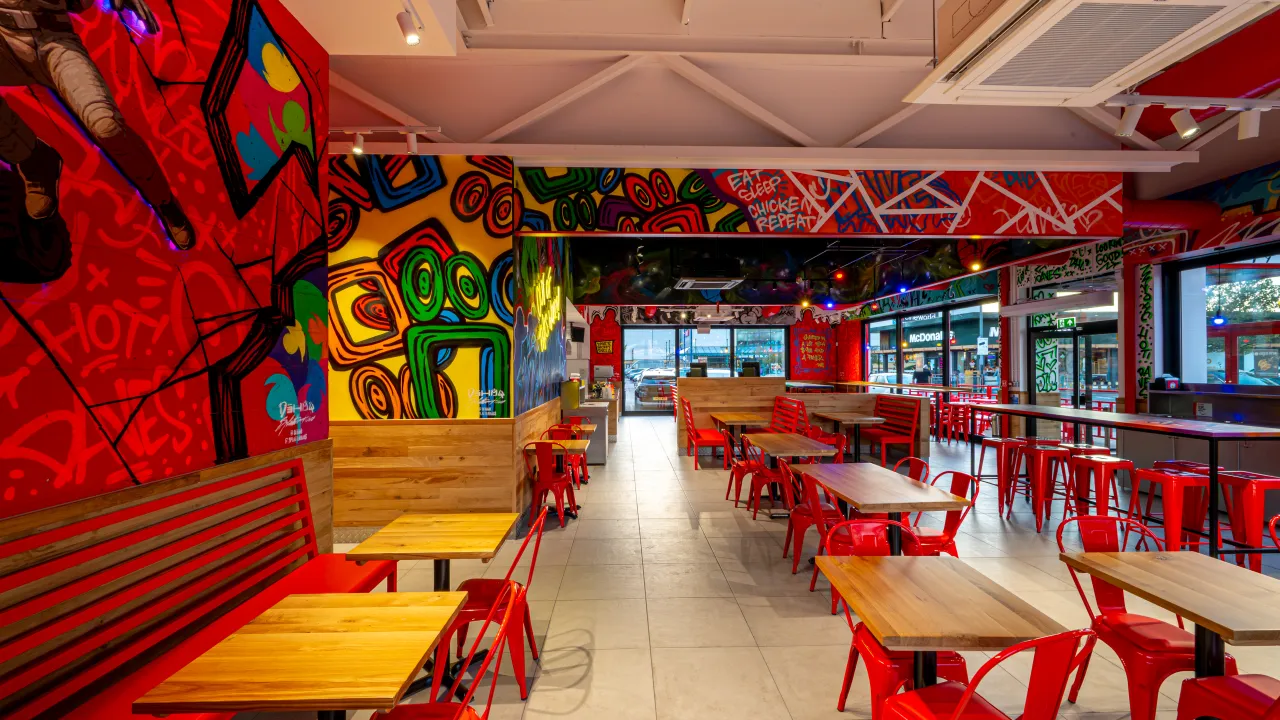 Interior view of Dave's Hot Chicken at Stevenage Leisure Park, Stevenage, UK, showcasing vibrant murals and red seating.
