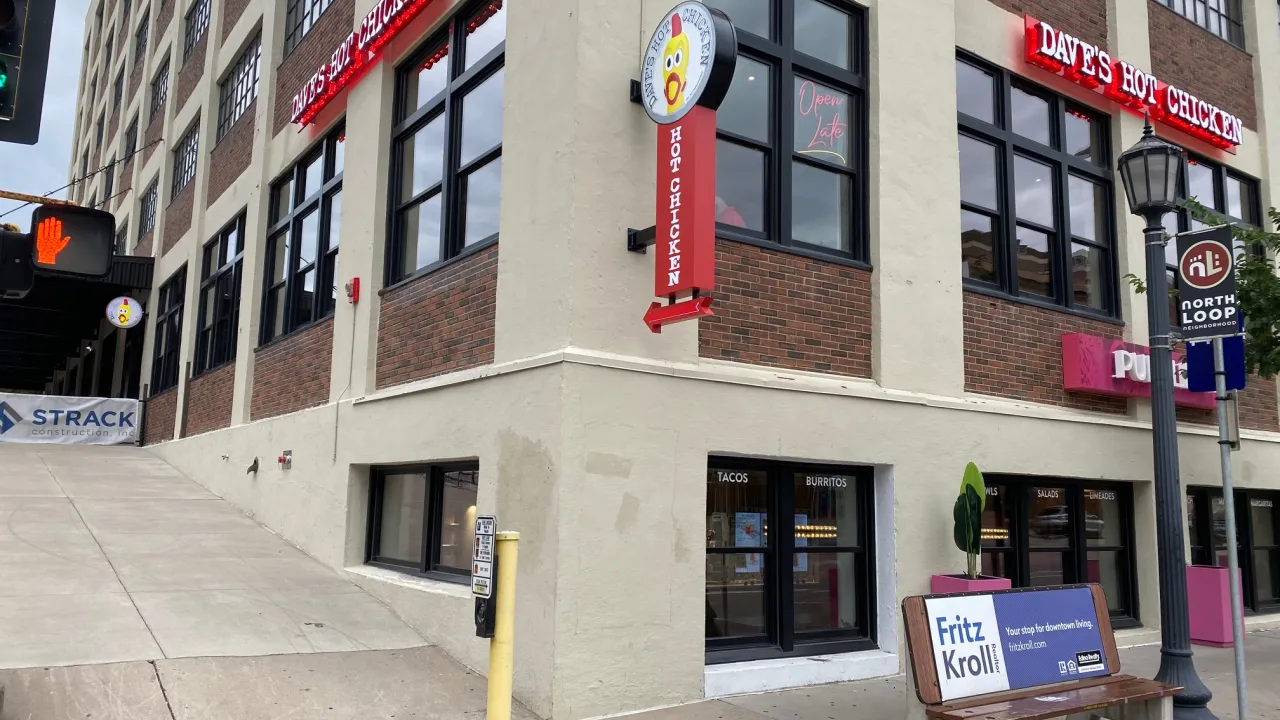 Exterior view of Dave's Hot Chicken on Washington Ave N, Minneapolis, MN, showcasing vibrant red signage and nearby street features.