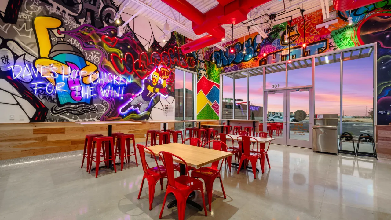 Interior view of Dave's Hot Chicken at 4182 W. 13400 S., Riverton, UT, showcasing vibrant murals and red seating.
