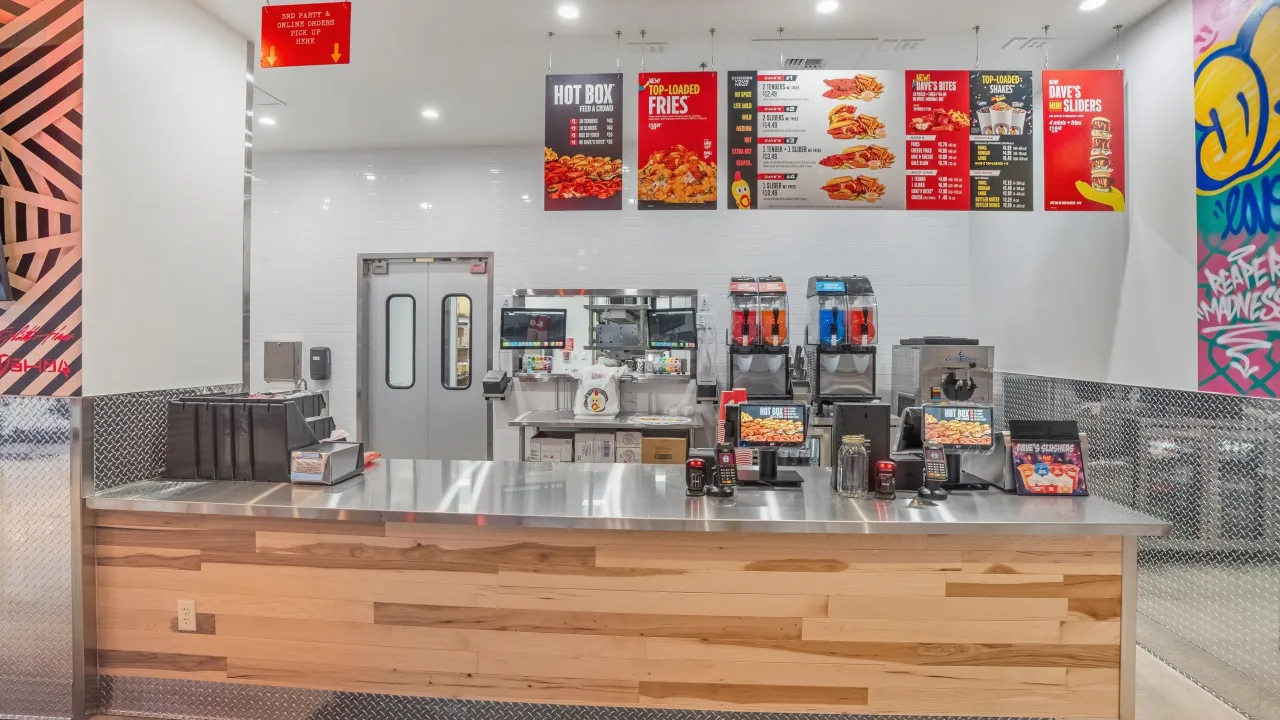 Interior view of Dave's Hot Chicken at 2650 32nd Ave S, Grand Forks, ND, showcasing a sleek counter and vibrant menu signage.