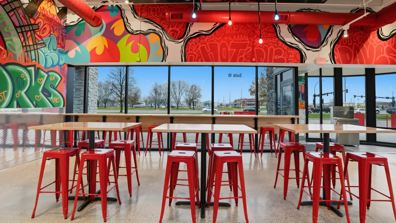 Interior view of Dave's Hot Chicken at 2650 32nd Ave S, Grand Forks, ND, showcasing vibrant murals and red furniture.