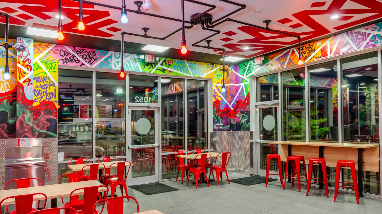 Interior view of Dave's Hot Chicken at 1052 N. Ballas Rd, Des Peres, MO, showcasing vibrant murals and red seating.