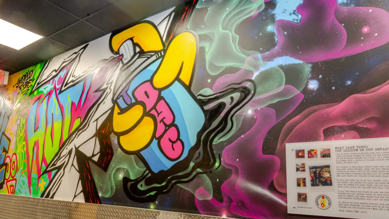 Interior view of Dave's Hot Chicken on N. Ballas Rd, Des Peres, MO, showcasing vibrant mural art and colorful ambiance.