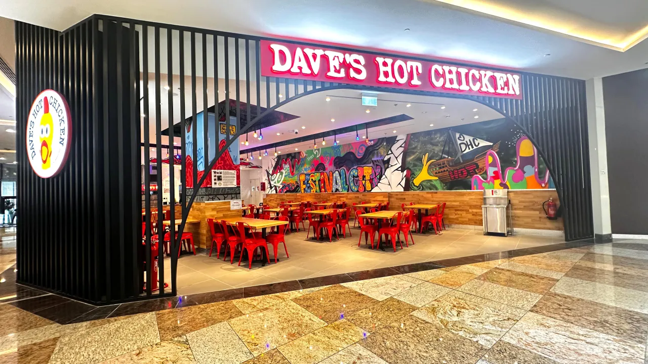 Interior view of Dave's Hot Chicken on Crescent Drive St, Dubai Festival City, Dubai, featuring vibrant murals and red seating.