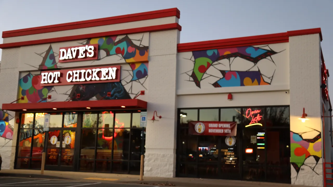 Exterior view of Dave's Hot Chicken at 435 Merchant Walk Square, Charlottesville, VA, showcasing vibrant murals and neon signage.