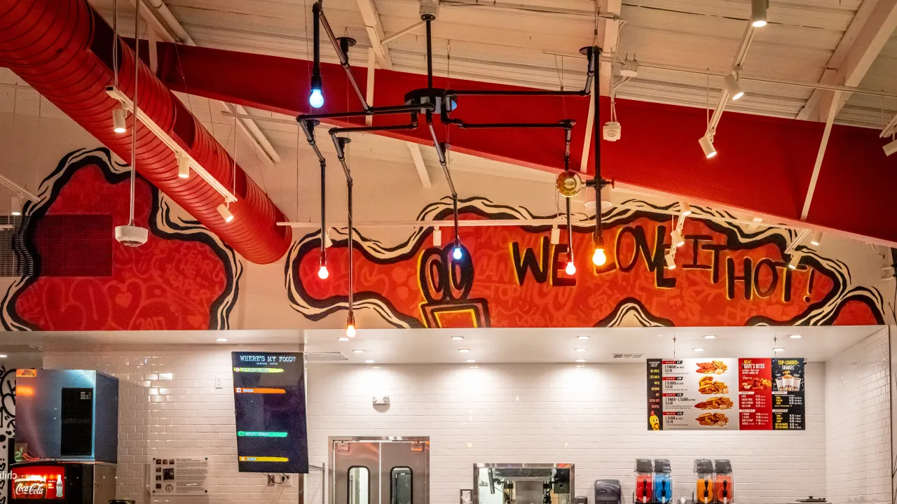 Interior view of Dave's Hot Chicken in Conway, AR, showcasing vibrant murals, unique lighting, and a welcoming ambiance.