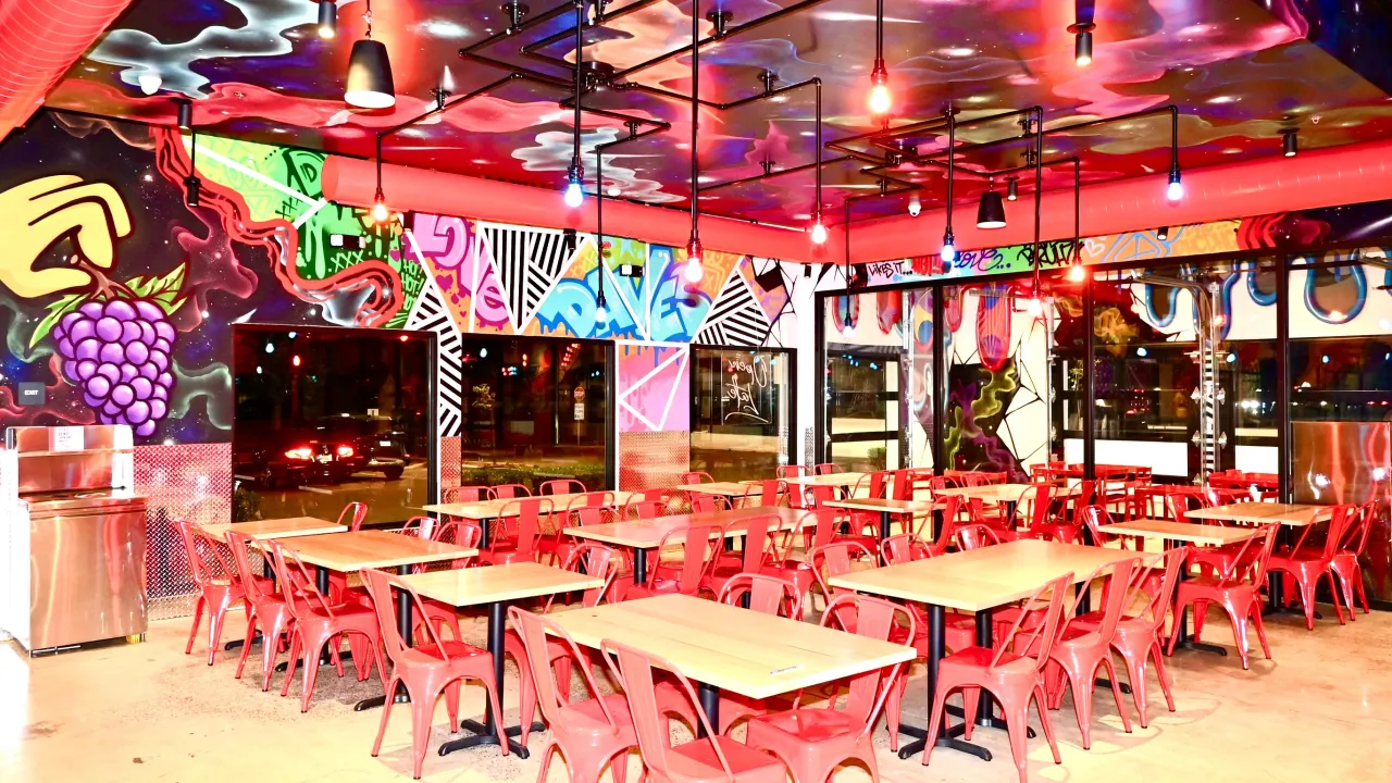 Interior view of Dave's Hot Chicken on E Shaw Avenue, Fresno, CA, showcasing vibrant murals and red seating.
