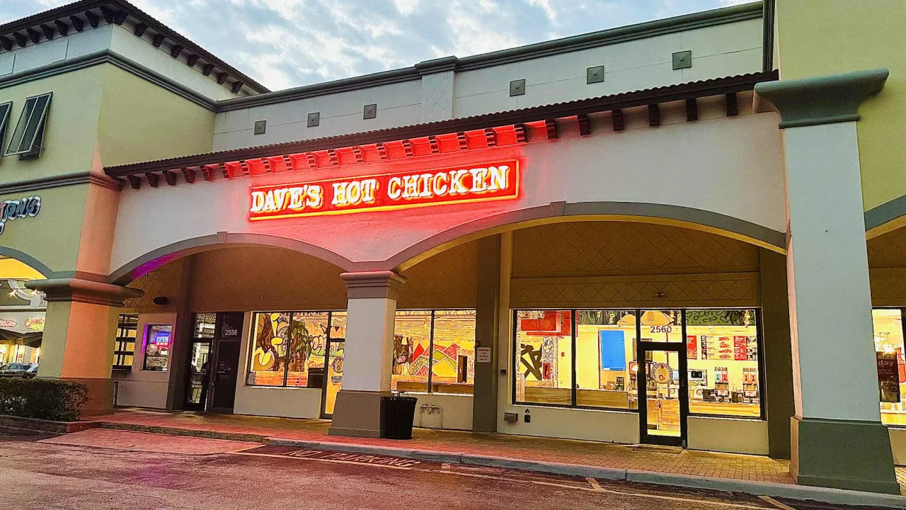 Exterior view of Dave's Hot Chicken at 2560 N. University Dr, Coral Springs, FL, featuring bright red signage and artistic windows.