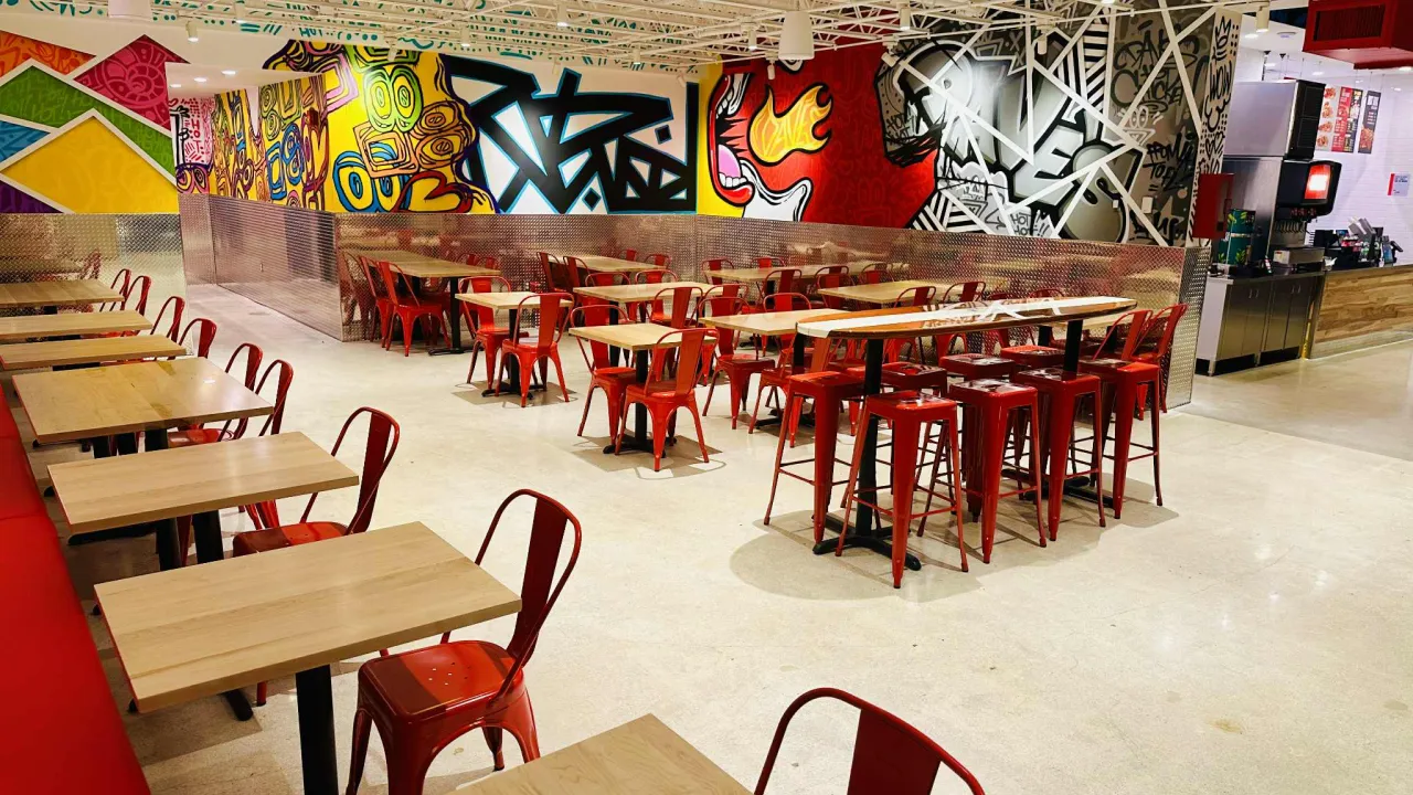 Interior view of Dave's Hot Chicken on N. University Dr, Coral Springs, FL, showcasing vibrant murals and red seating.