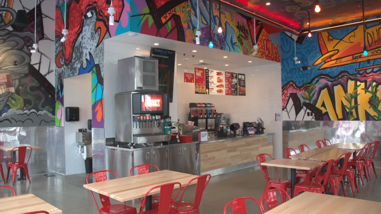 Interior view of Dave's Hot Chicken at 1805 S.E. Delaware Avenue, Ankeny, IA, showcasing vibrant murals and cozy seating.
