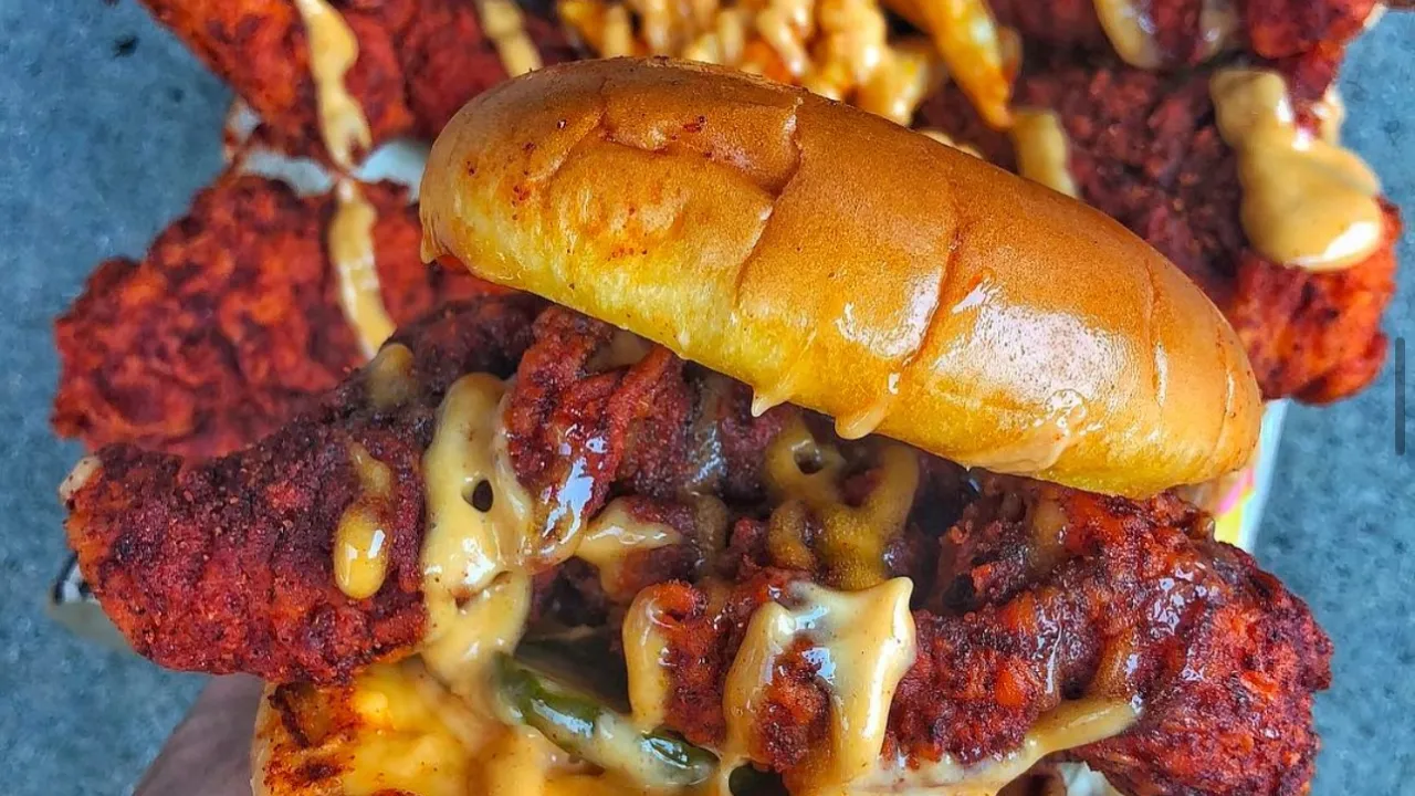 Juicy chicken sandwich with spicy sauce at Dave's Hot Chicken on Macleod Trail SE, Calgary, AB, showcasing vibrant colors.