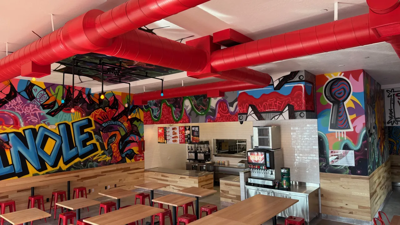 Interior view of Dave's Hot Chicken on Pinole Valley Rd, Pinole, CA, showcasing vibrant murals and red accents.