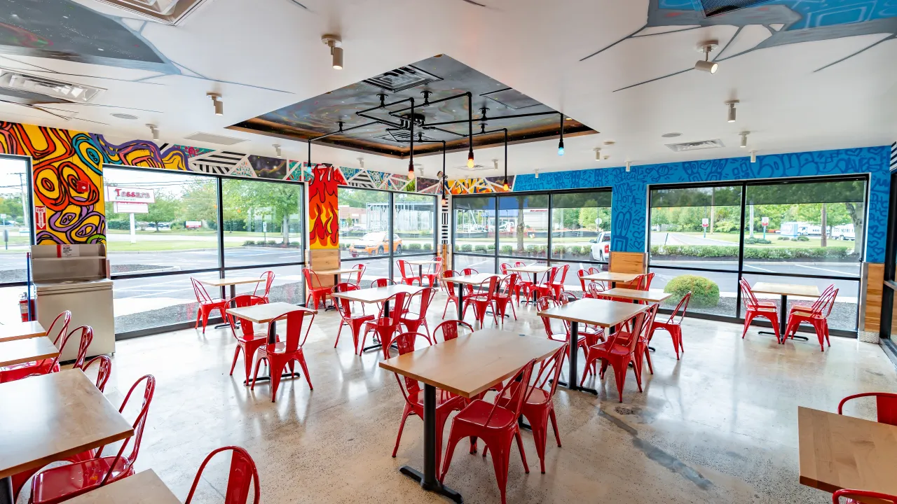 Interior view of Dave's Hot Chicken at 770 Route 33, Hamilton, NJ, showcasing vibrant murals and red seating.