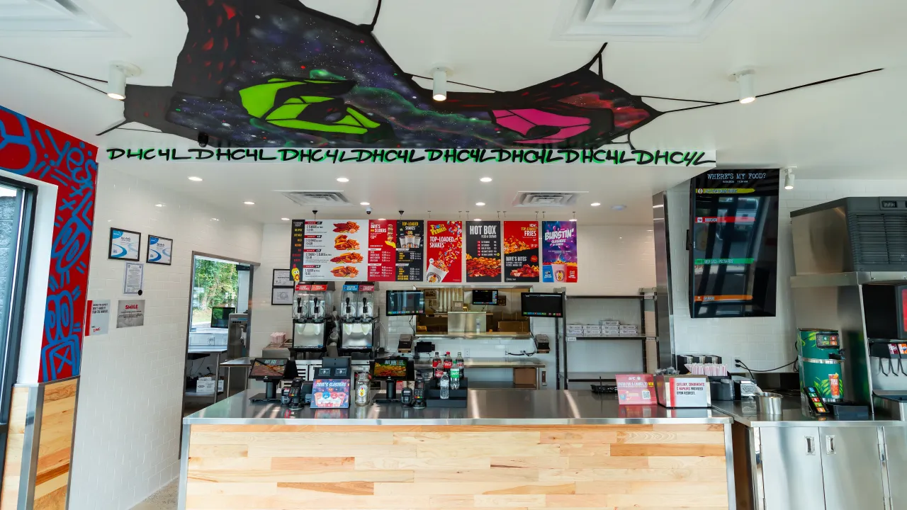 Interior view of Dave's Hot Chicken on Route 33, Hamilton, NJ, showcasing vibrant murals and a modern counter.