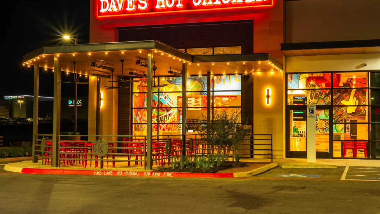 Exterior view of Dave’s Hot Chicken at 18476 I-35 N. Frontage Rd, Schertz, TX, featuring vibrant murals and red seating.