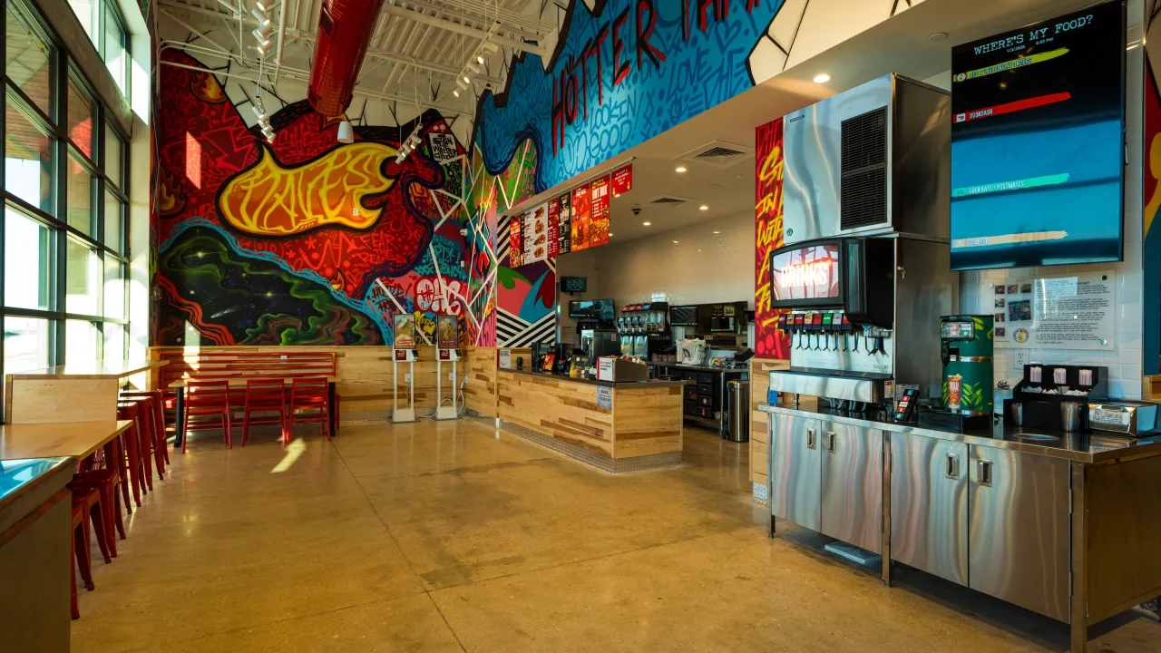 Interior view of Dave's Hot Chicken on I-35 N Frontage Rd, Schertz, TX, featuring vibrant murals and a modern counter.