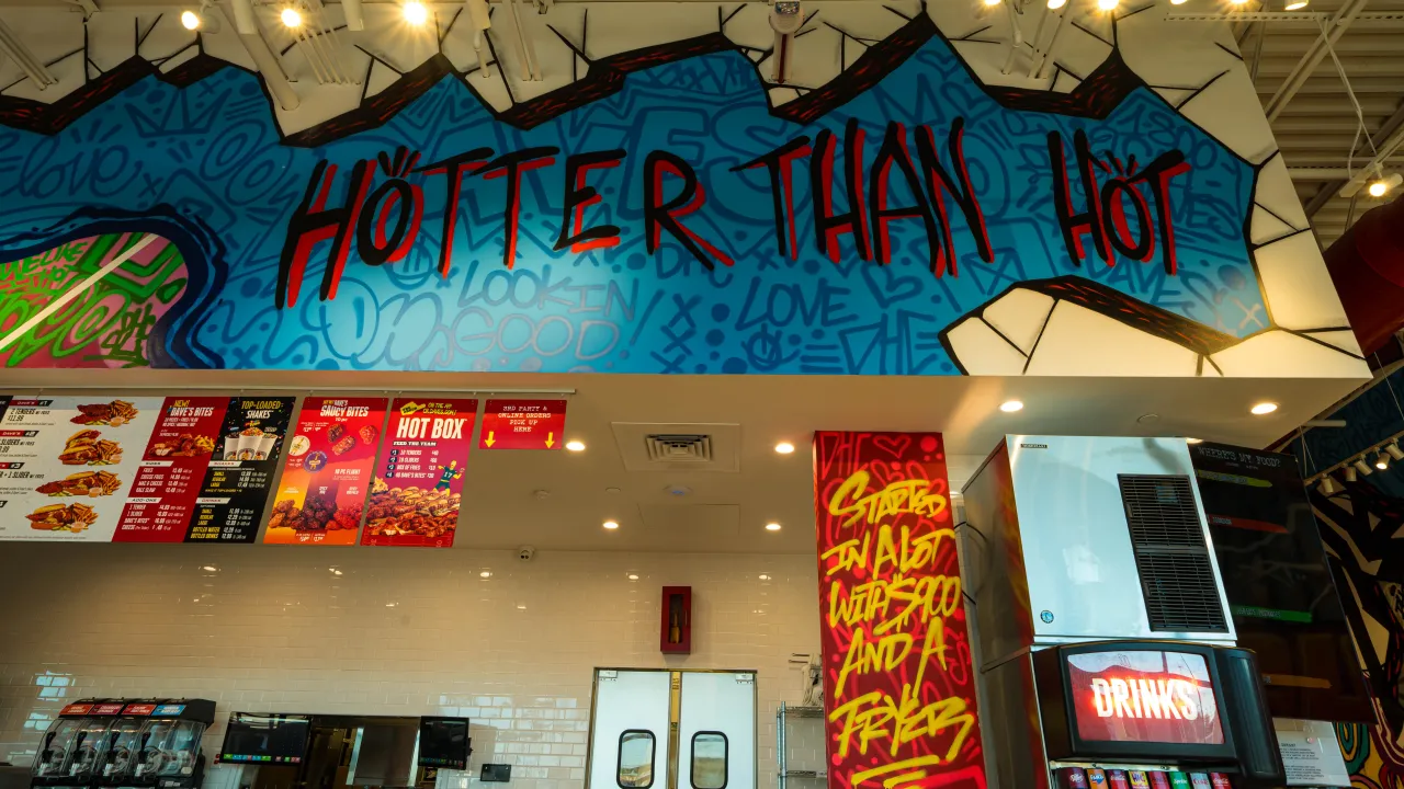 Interior view of Dave's Hot Chicken at 18476 I-35 N Frontage Rd, Schertz, TX, showcasing vibrant murals and menu displays.
