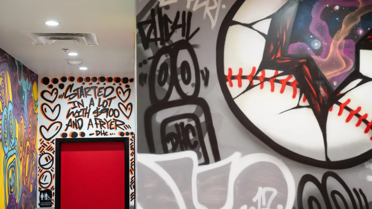 Interior view of Dave's Hot Chicken at 5282 Campbell Blvd, Nottingham, MD, featuring vibrant graffiti art and restroom sign.