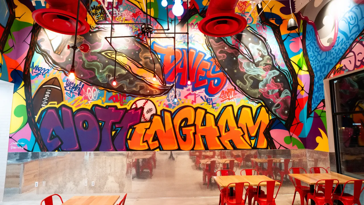 Interior view of Dave's Hot Chicken at 5282 Campbell Blvd, Nottingham, MD, showcasing vibrant graffiti and red seating.