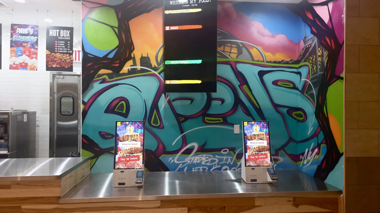 Interior view of Dave's Hot Chicken at 9015 Queens Center, Elmhurst, NY, showcasing vibrant graffiti and ordering kiosks.
