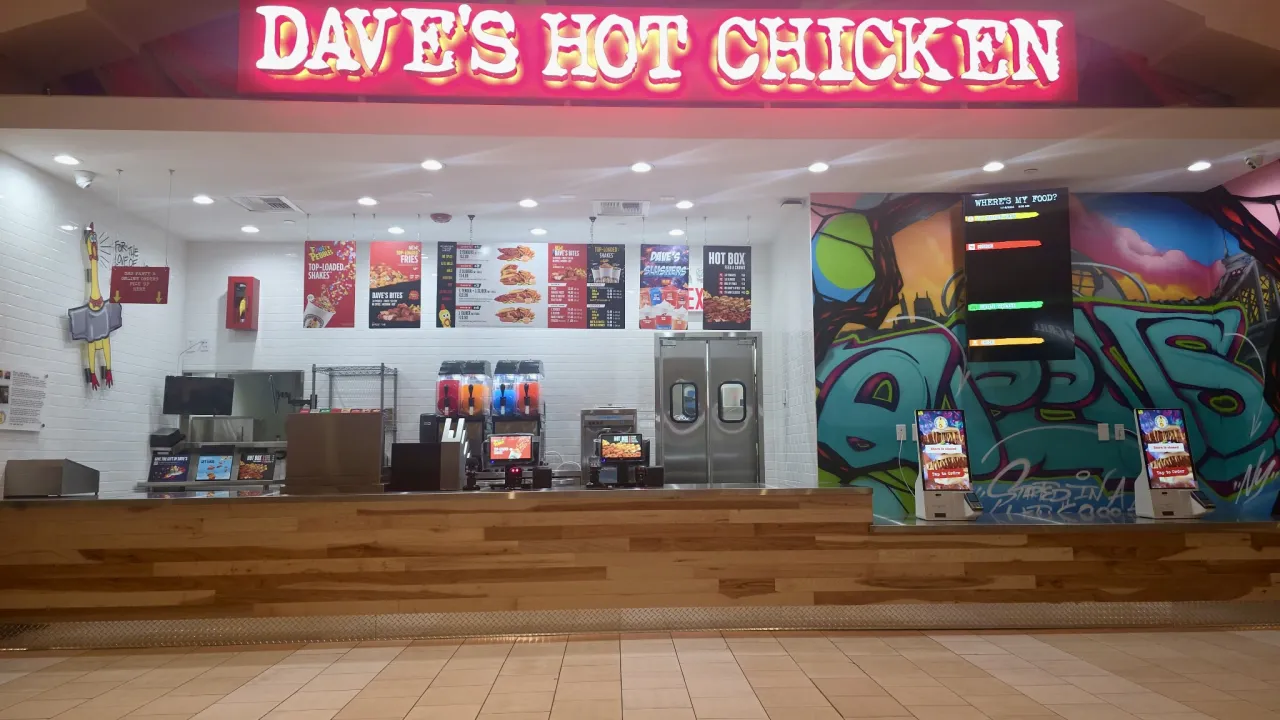 Interior view of Dave's Hot Chicken at 9015 Queens Center, Elmhurst, NY, showcasing vibrant murals and a modern counter.