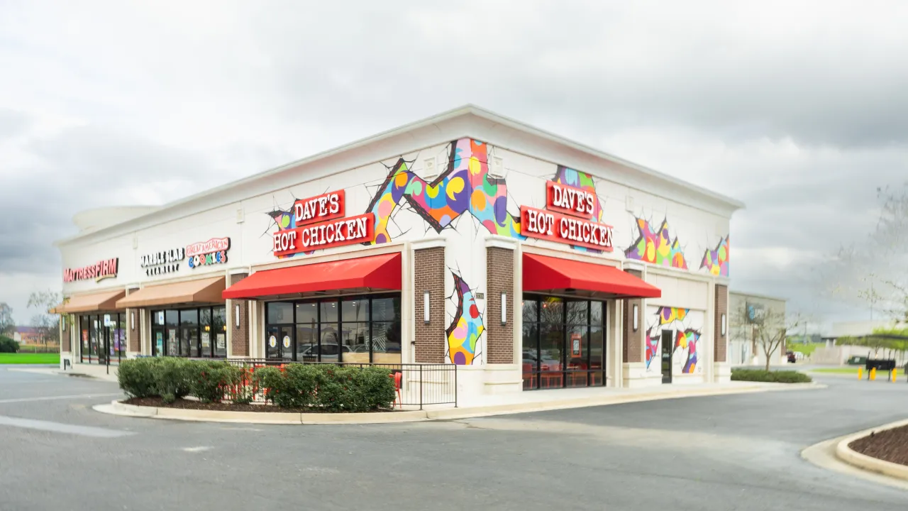 Exterior view of Dave’s Hot Chicken on Crossing Cir, Denham Springs, LA, featuring colorful murals and red awnings.
