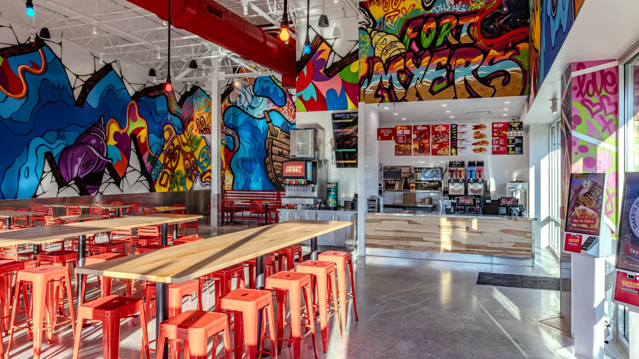 Interior view of Dave's Hot Chicken on Dani Dr, Fort Myers, FL, showcasing vibrant murals and red seating.
