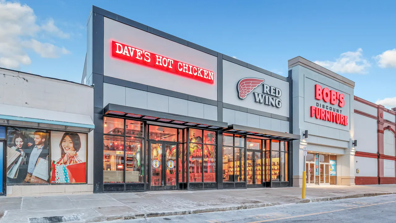 Exterior view of Dave's Hot Chicken on 56th Ave, Laveen, AZ, showcasing vibrant signage and large glass windows.