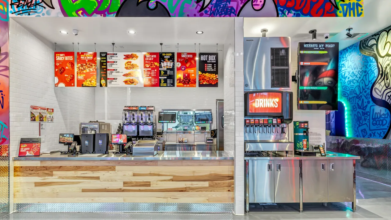 Interior view of Dave’s Hot Chicken on 56th Ave, Laveen, AZ, showcasing colorful menu boards and modern counters.