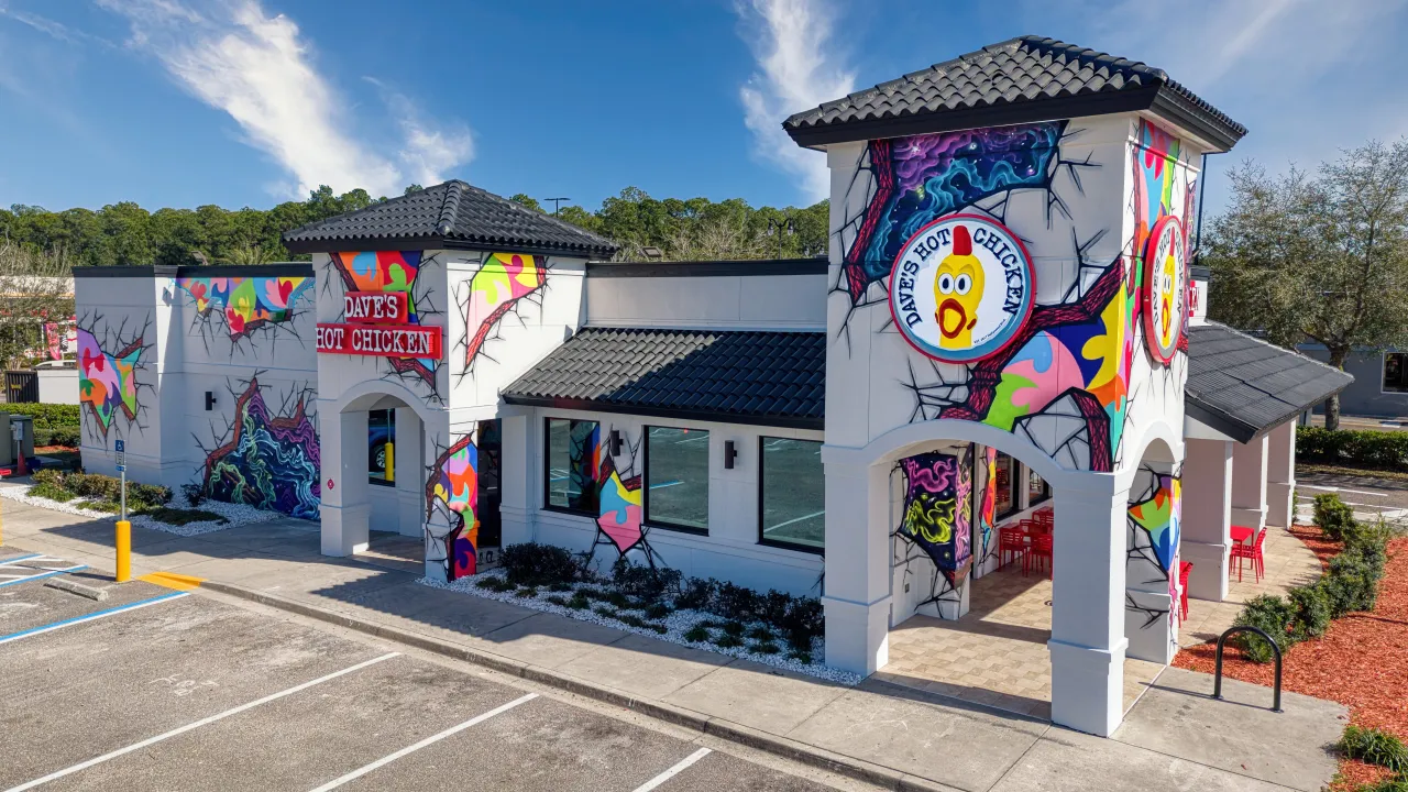 Exterior view of Dave's Hot Chicken on Skymarks Drive, Jacksonville, FL, showcasing vibrant murals and bold signage.