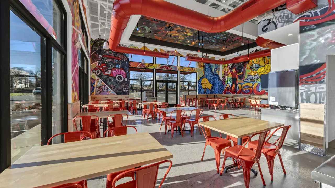 Interior view of vibrant dining area at 1102 Trust Ave, Augusta, GA, featuring colorful murals and modern red chairs.