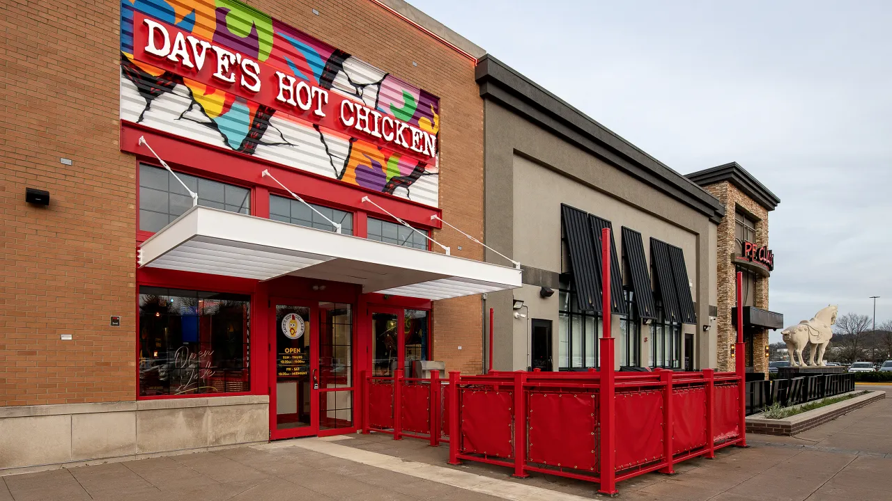 Exterior view of Dave's Hot Chicken at 3265 W. Market Street, Fairlawn, OH, showcasing vibrant mural and red seating.