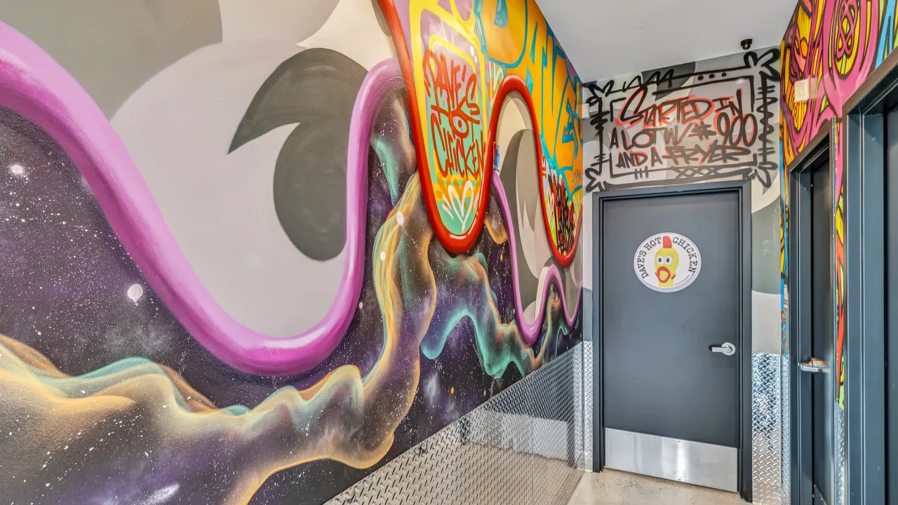 Interior view of Dave's Hot Chicken on Federal Rd, Brookfield, CT, showcasing vibrant murals and stylish decor.