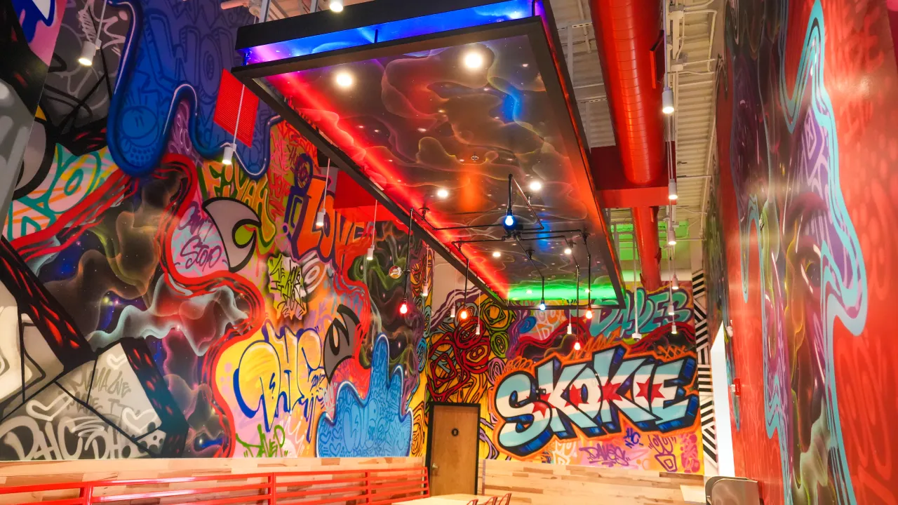 Vibrant interior of a restaurant at 5530 W Touhy Ave, Skokie, IL, featuring colorful graffiti murals and modern lighting.