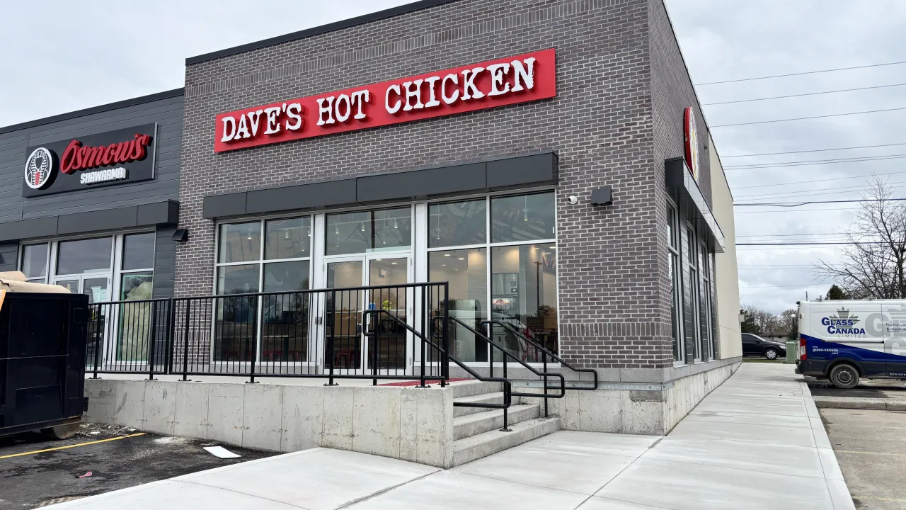 Exterior view of Dave's Hot Chicken at 765 Wonderland Rd. S., London, ON, showcasing large windows and bold signage.