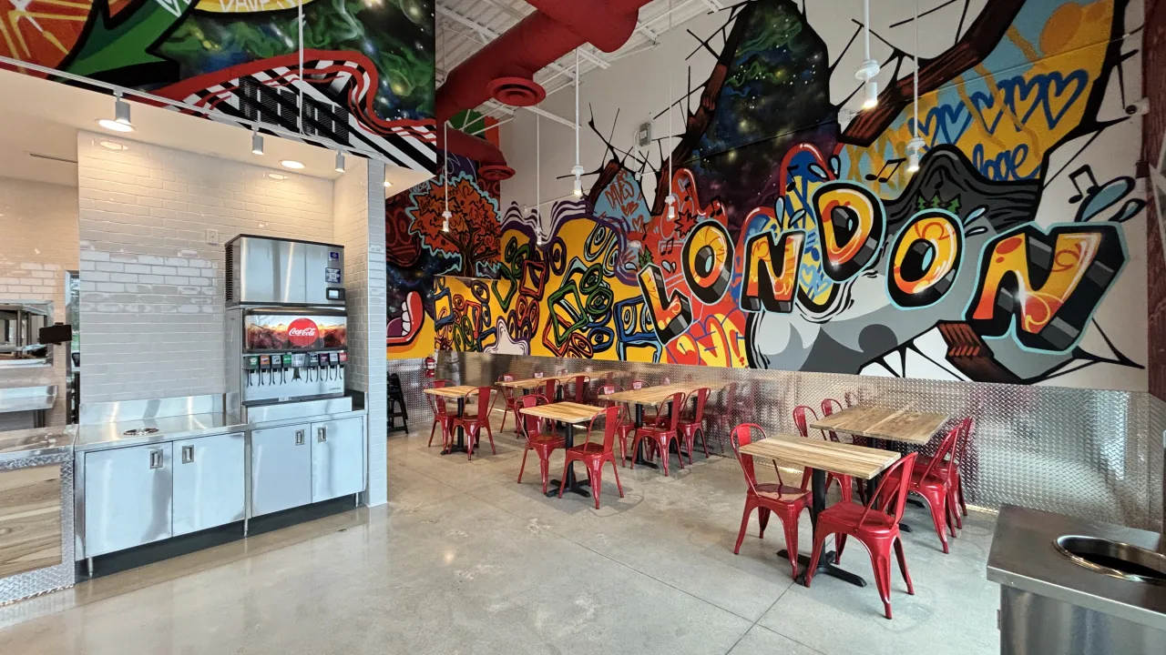 Interior view of a vibrant eatery at 765 Wonderland Rd. S., Unit 106-765, London, ON, featuring colorful murals and red chairs.